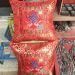 This handmade Tibetan silk brocade cushion cover, crafted in Nepal, features the Endless Knot, symbolizing unity and harmony, bringing sacred beauty to your home.