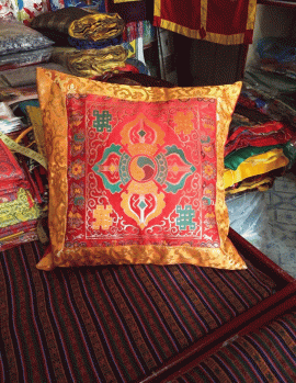This handmade cushion cover from Nepal showcases a vibrant red silk brocade featuring the sacred double dorje symbol, inviting mindfulness and serenity into your sacred space.