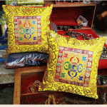 This handmade Tibetan cushion cover, crafted by skilled artisans in Nepal, features a vibrant yellow double dorje, symbolizing the harmony of wisdom and compassion for your meditation space.