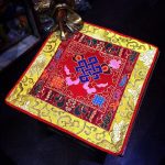 This handmade Tibetan altar cloth, crafted in Nepal, features the endless knot and lotus, symbolizing wisdom and interconnectedness, enriching your meditation space with spiritual significance.