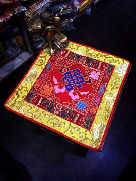 This handmade Tibetan altar cloth, crafted in Nepal, features the endless knot and lotus, symbolizing wisdom and interconnectedness, enriching your meditation space with spiritual significance.
