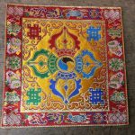 This handmade yellow silk brocade double dorje shrine placemat, crafted by skilled artisans in Nepal, creates a sacred space for meditation and prayer, embodying the essence of compassion and wisdom.